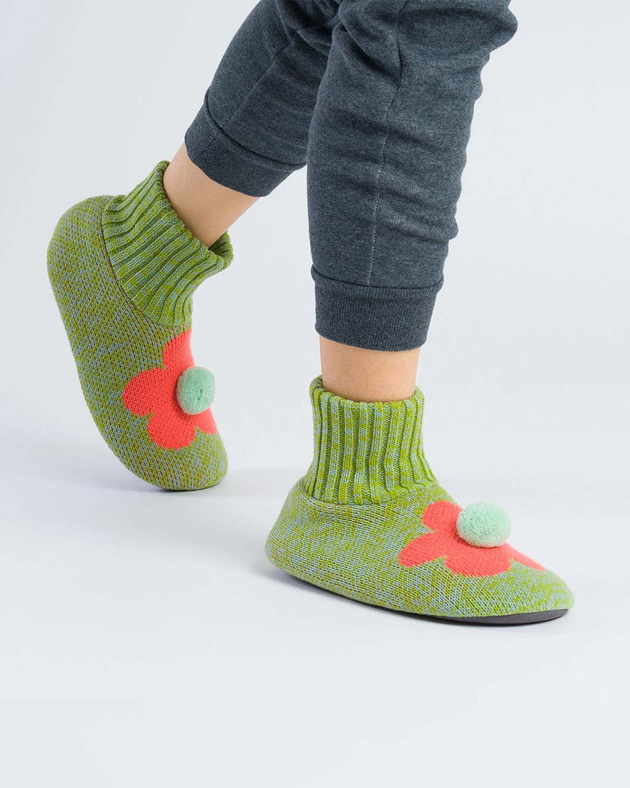 model wearing green and stone marled slippers with coral flower and pom