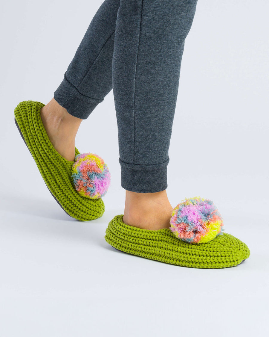 model wearing green slippers with multicolor poms on each