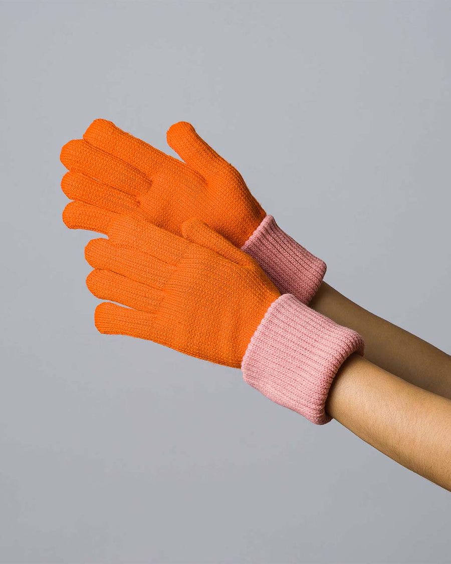 model wearing folded orange knit gloves with light pink interior