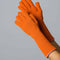 model wearing unfolded orange knit gloves with light pink interior