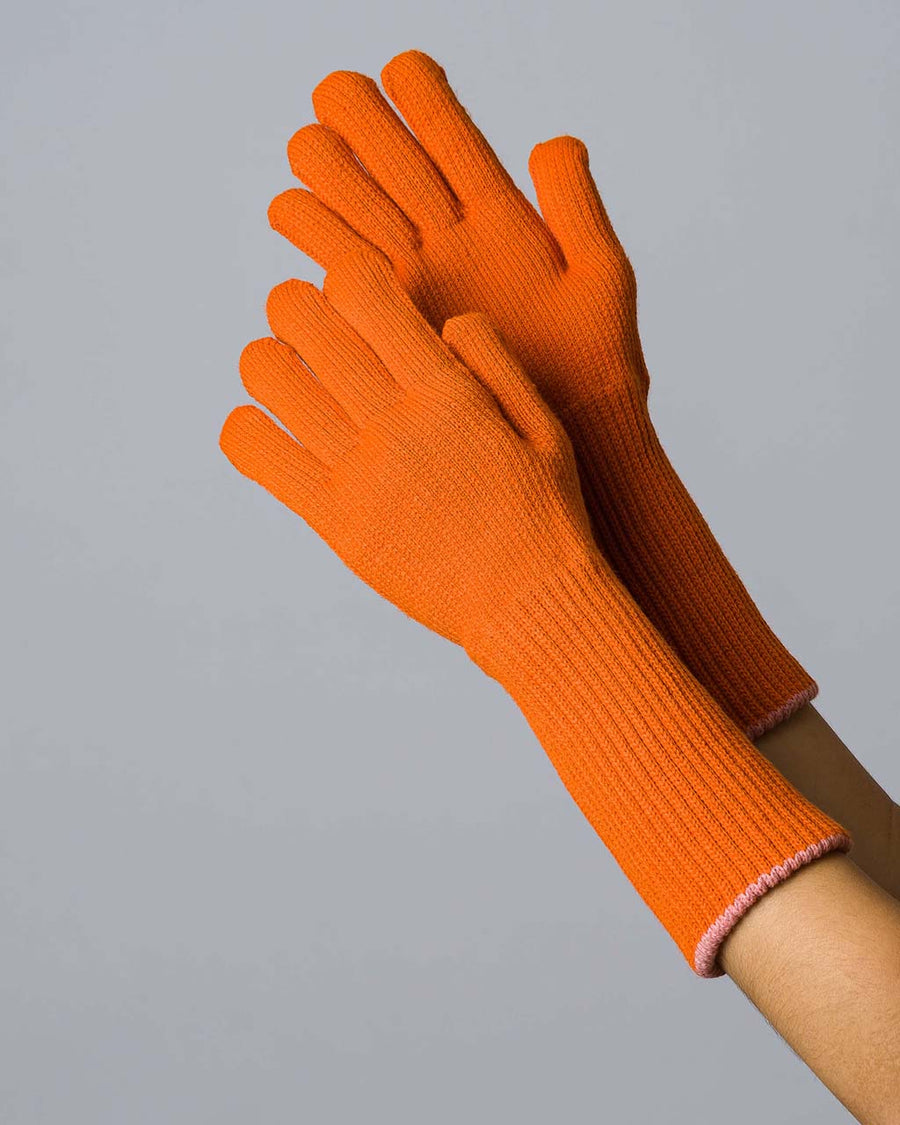 model wearing unfolded orange knit gloves with light pink interior