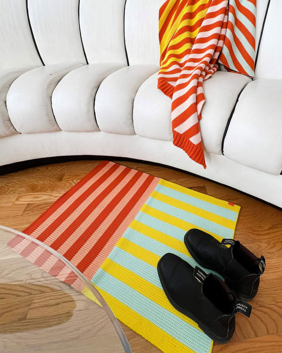 vertical and horizontal stripe mini rug in jade/yellow and burnt orange/peach on floor