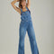 model wearing denim flare overalls with oversized front pocket and wrangler patch