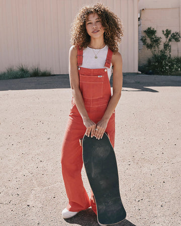 model wearing red flare overalls with oversized front pocket and wrangler patch