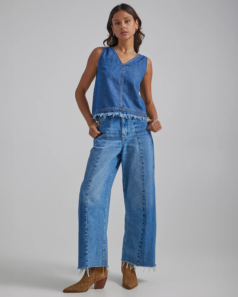 model wearing high waisted wide leg denim with front seams large patch pockets and raw hem