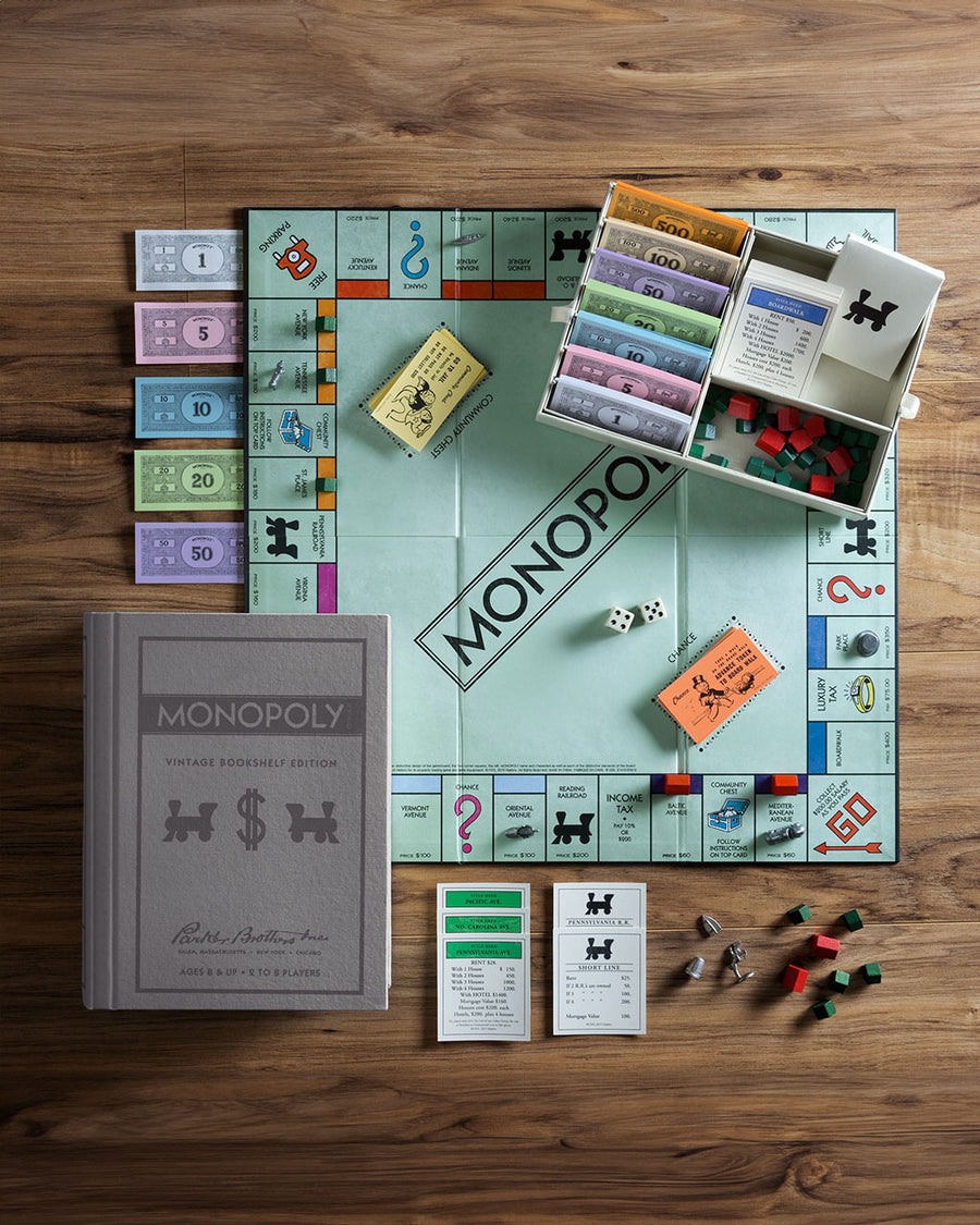 game board and pieces of monopoly vintage board game with retro bookshelf cover