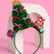 green tulle christmas tree with colorful bows, gold star and stacked christmas presents leaned on a stand