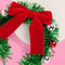 side view of green tinsel headband with red velvet bow and ornaments