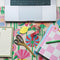 closeup of desk accessories and a laptop sitting on the floral desk pad