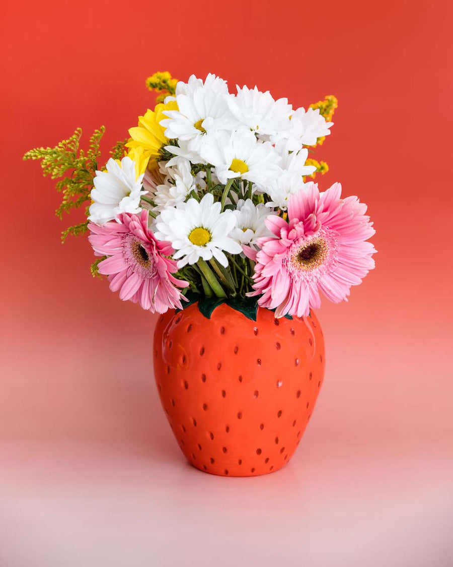 strawberry vase with floral arrangement inside