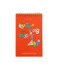 red desk calendar with rainbow bubble 'evolving everyday' graphic with flowers and top spiral bound
