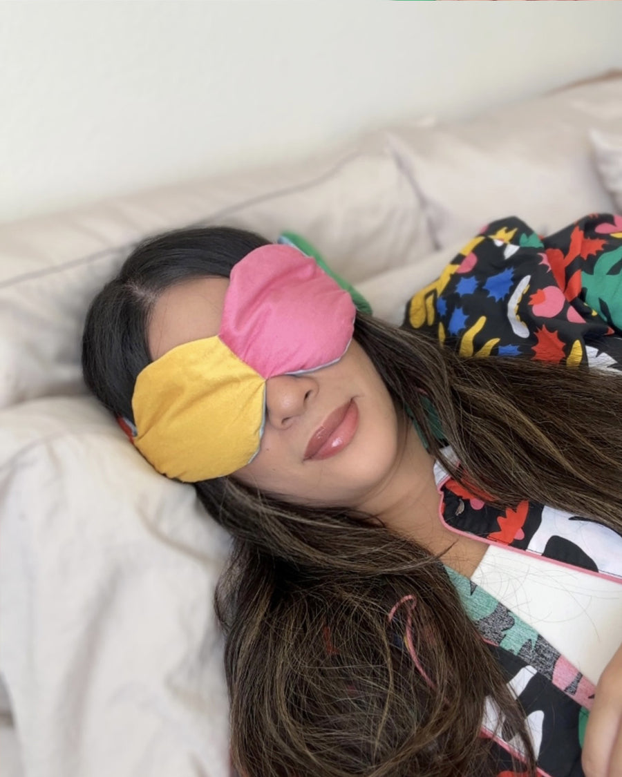 Weighted sleep mask on woman laying on a beige sofa