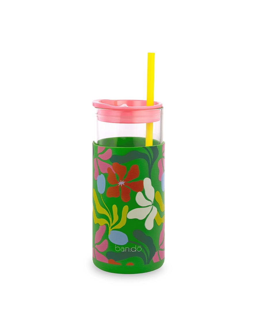 backview of glass 20 oz tumbler with pink lid, yellow straw and sleeve with a green abstract floral print