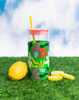 glass 20 oz tumbler with pink lid, yellow straw and sleeve with a green abstract floral print with lemons next to it