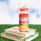 glass 20 oz tumbler with red lid, yellow straw, and rainbow ombre sleeve with white text 'make time to make magic' across the front on a stack of notebooks