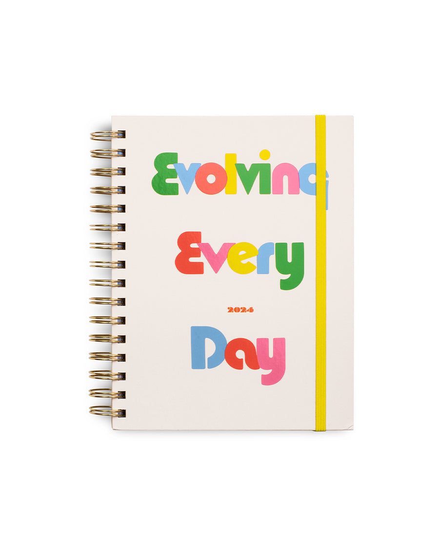 12 month medium planner with cream cover and colorful 'evolving everyday' text and yellow elastic closure