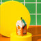 ceramic orange juice shaped ornament on yellow pedestal 