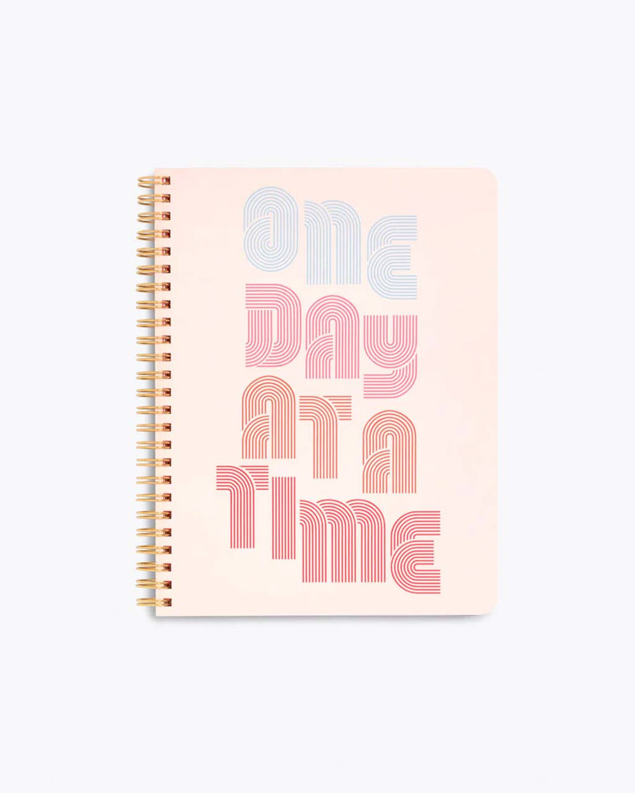 spiral bound notebook cover in blush pink with "ONE DAY AT A TIME" text graphic