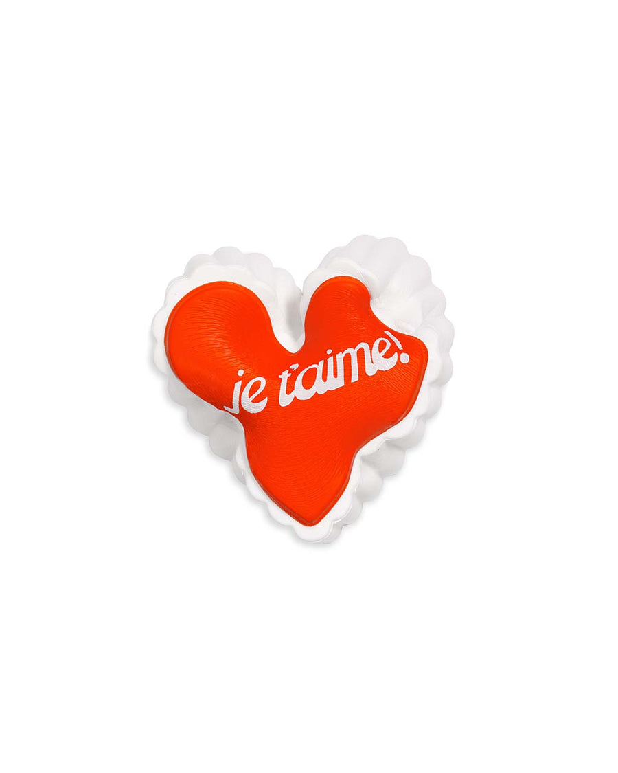 squished red heart shaped de-stress ball with white scalloped trim and white 'je t'aime!' across the front