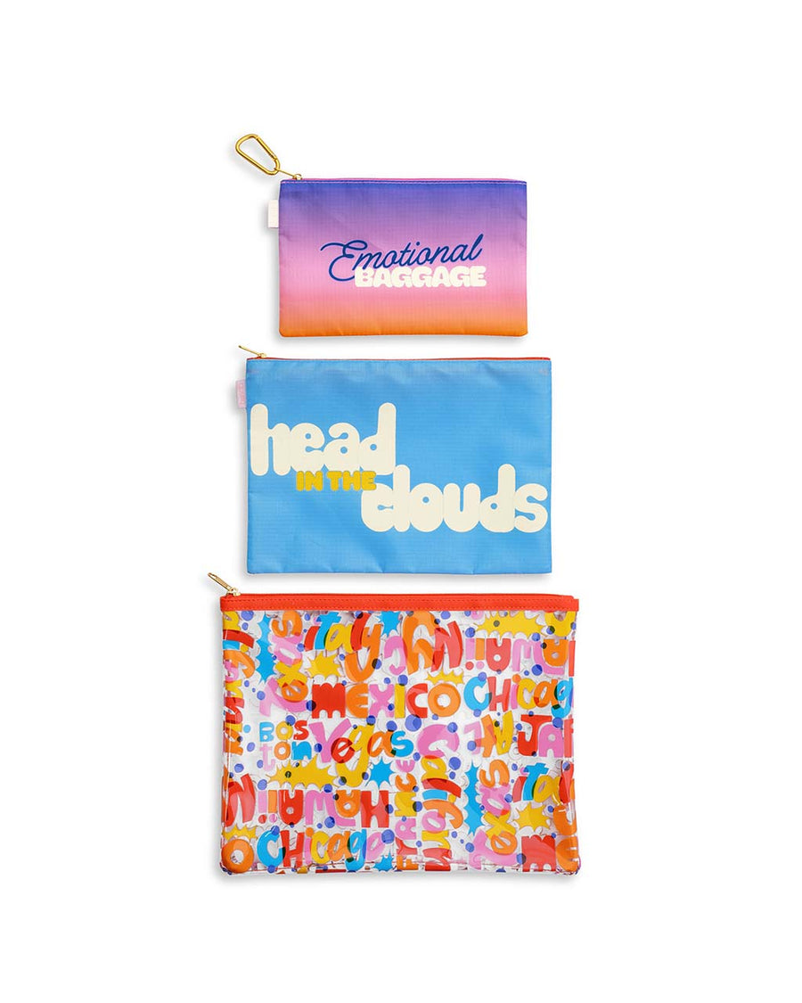 up close of set of three travel pouches: ombre 'emotional baggage', blue 'head in the clouds' and colorful cities names