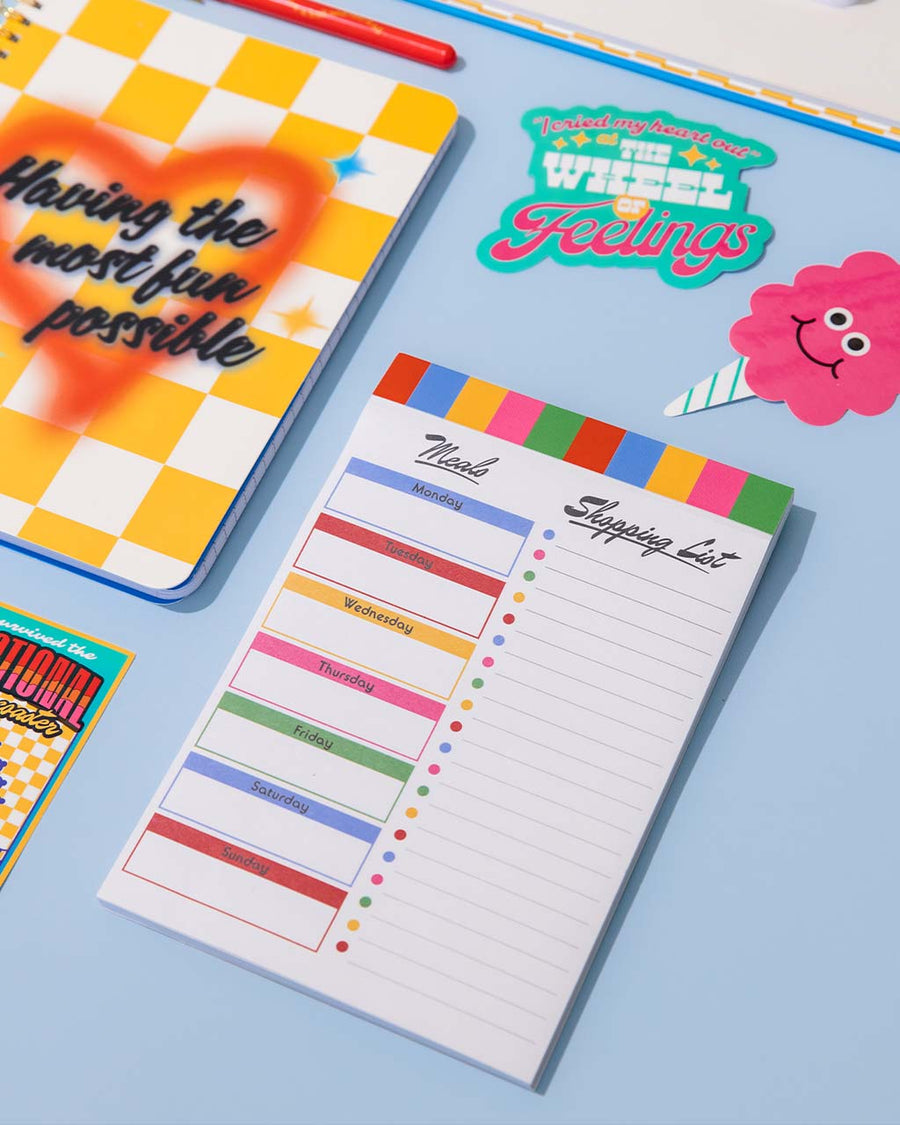 colorful stripe meal and shopping list notepad with magnetic back on table with notebook adn stickers