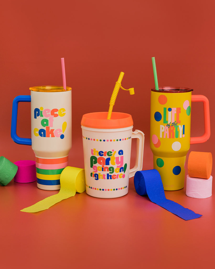 cream mega trucker cup with vibrant 'there's a party going on right here!' across the front, red lid, and yellow straw alongside two stainless steel tumblers