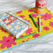 Close up of yellow and pink lap desk, with a planner and scattered colorful ink pens