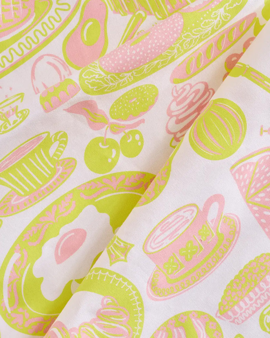 up close of light pink tea towel with yellow and pink breakfast food print