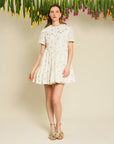 model wearing white tiered mini dress with delicate floral print and embellished collar