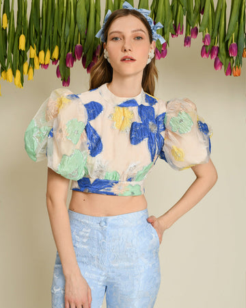 model wearing peach cropped top with large puff sleeves and blue, yellow and green flower print