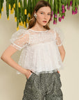 model wearing white tulle cropped top with dainty white flower print and sheer puff sleeves