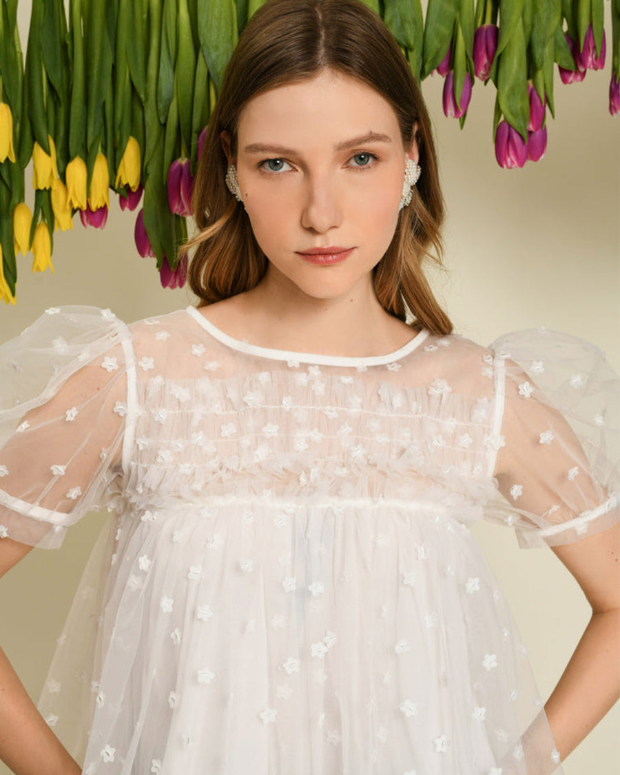 model wearing white tulle cropped top with dainty white flower print and sheer puff sleeves