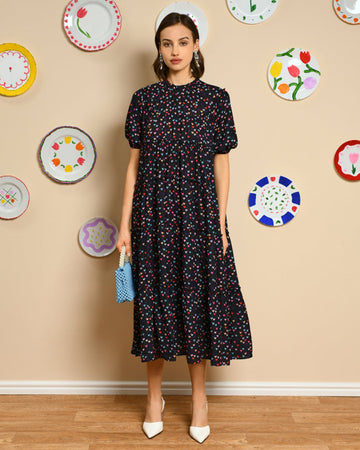 model wearing black tiered midi dress with slight puff sleeves and all over multi heart print