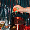 hand with green nail polish holding the cherry wine stopper, surrounded by drinks and tinsel
