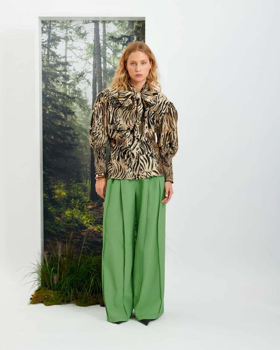 Full body view of model wearing a leopard print top and green wide leg trousers