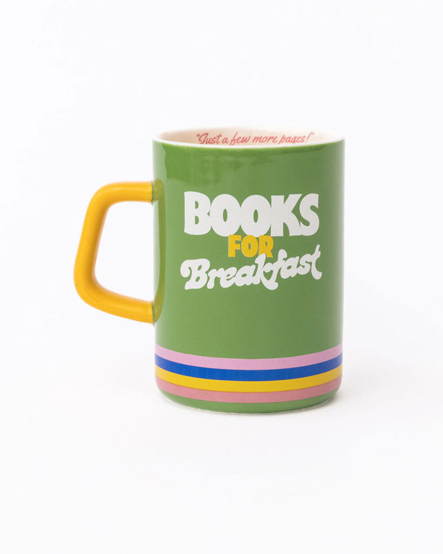 green ceramic mug with yellow handle, rainbow stripe bottom, 'books for breakfast' across the front and 'just a few more pages!' in the inside