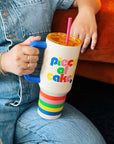 Mega Piece of Cake tumbler in hands of person wearing a denim jumpsuit