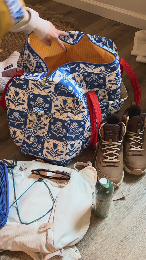 model packing with blue and white folk floral duffel bag