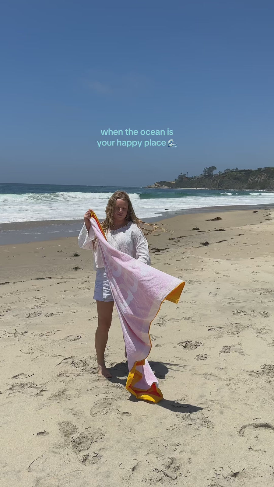 model waving 'always better together' towel in the wind on the beach