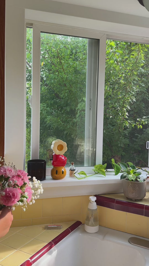 model putting a colorful bouquet of flowers in a stacked white flower, apple, and smiley stacked vase