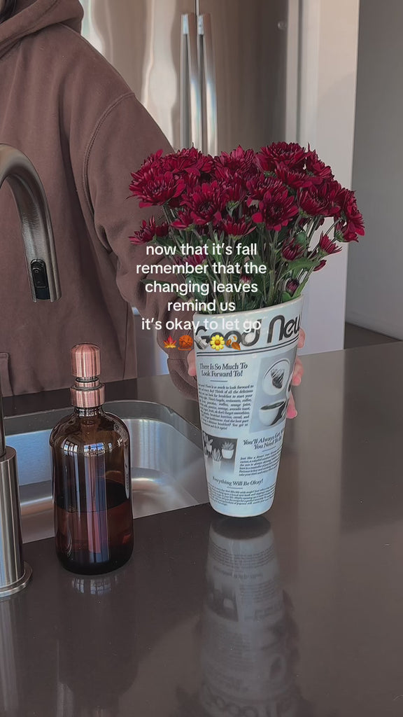 model putting red flowers in rolled newspaper vase