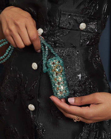 Closeup of person black dress holding an aqua beaded lipstick bag