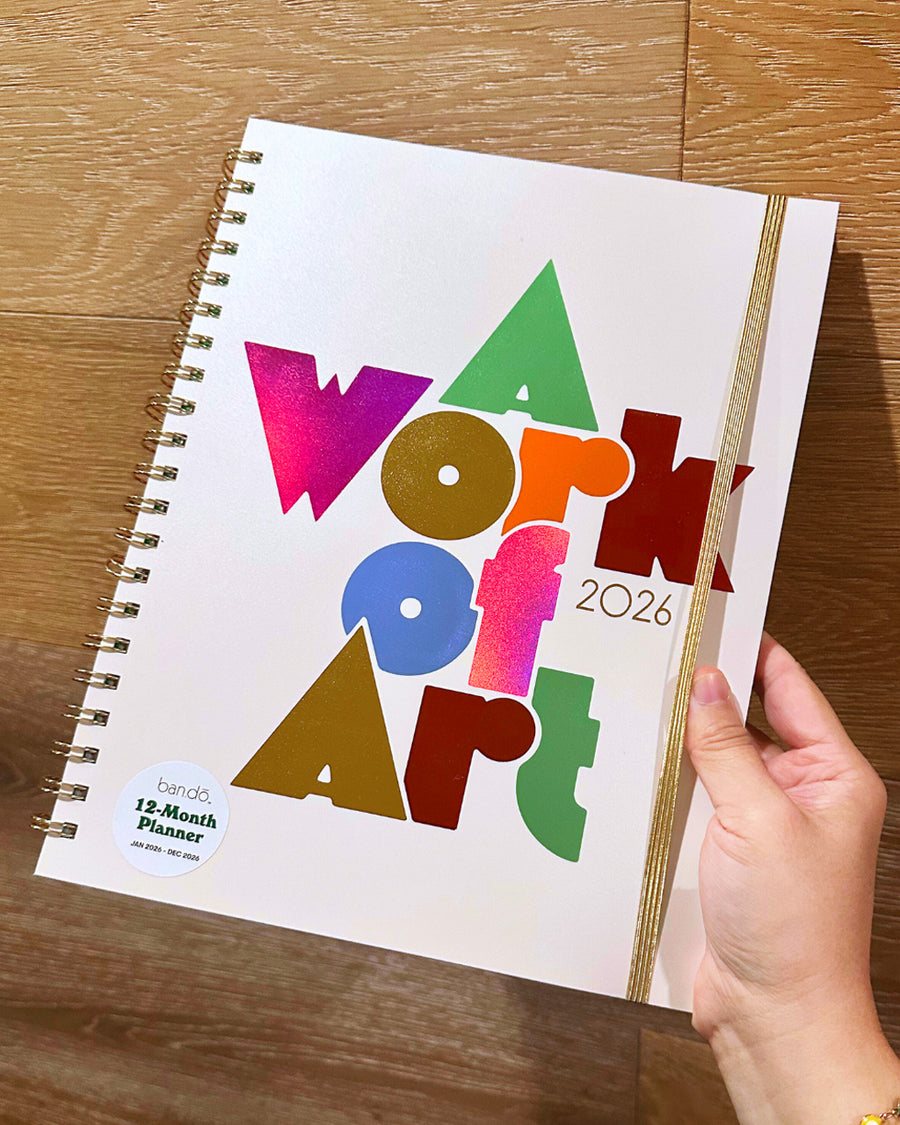 Hand holding a planner, with the words A Work of Art in metallic foil