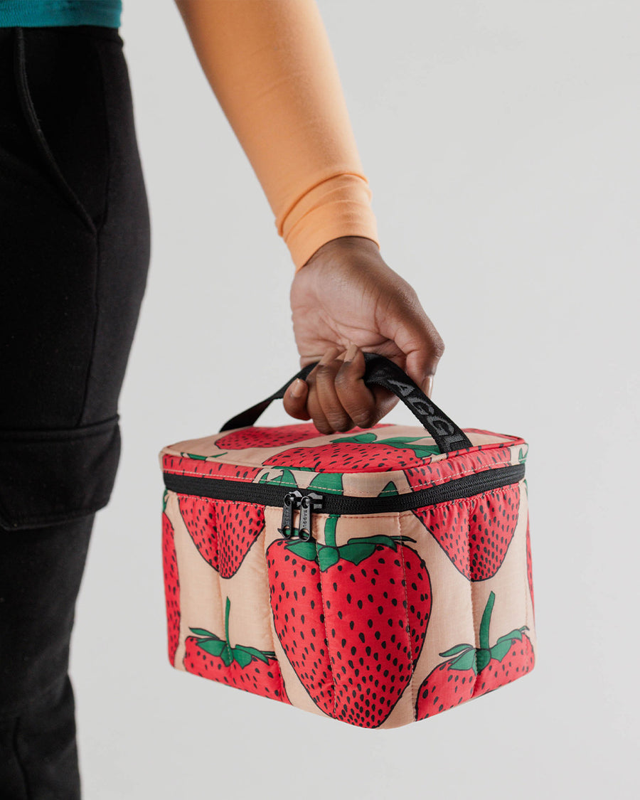 model holding baggu puffy lunch bag with pink ground and all over strawberry print