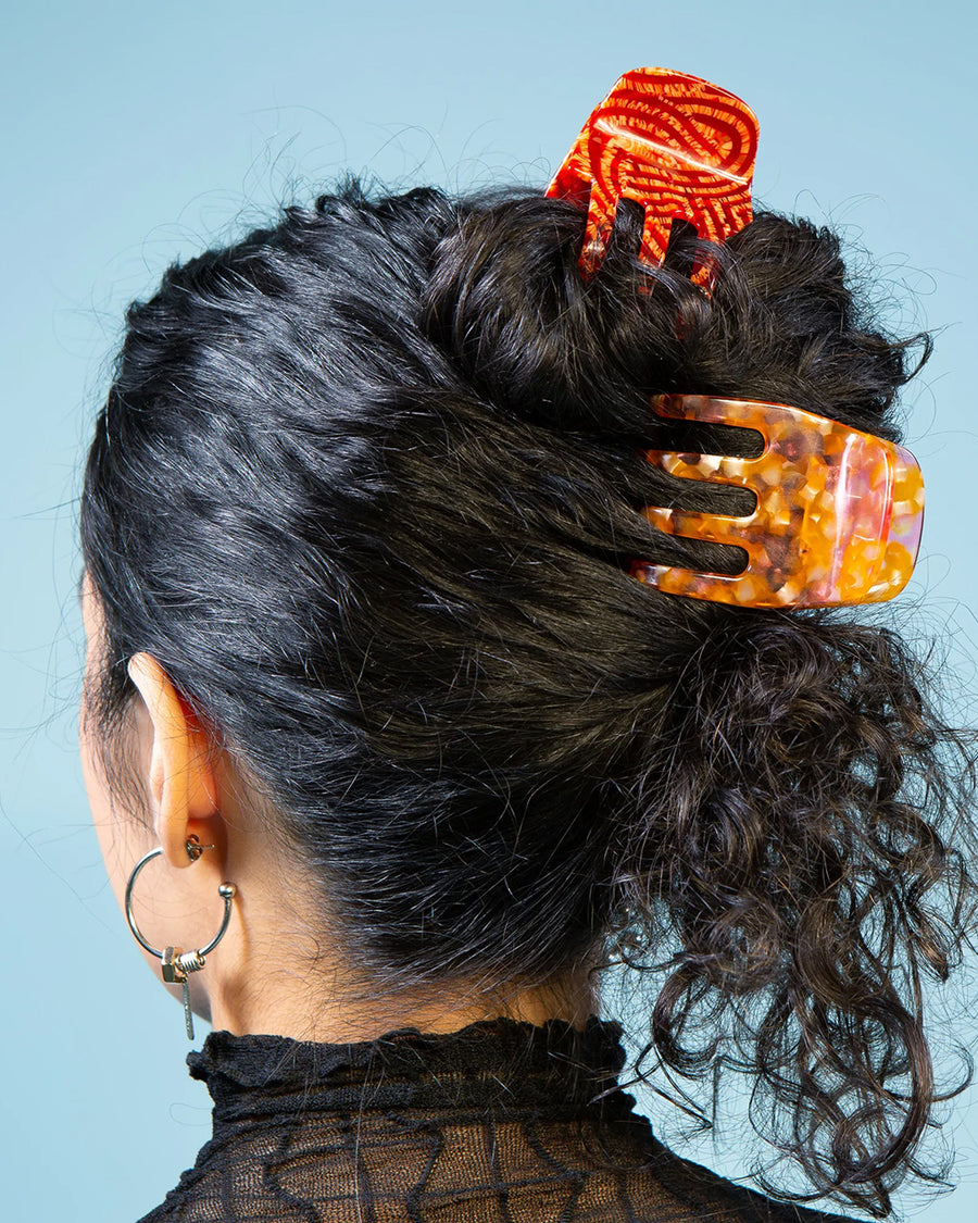 model wearing large orange and pink speckled hair claw