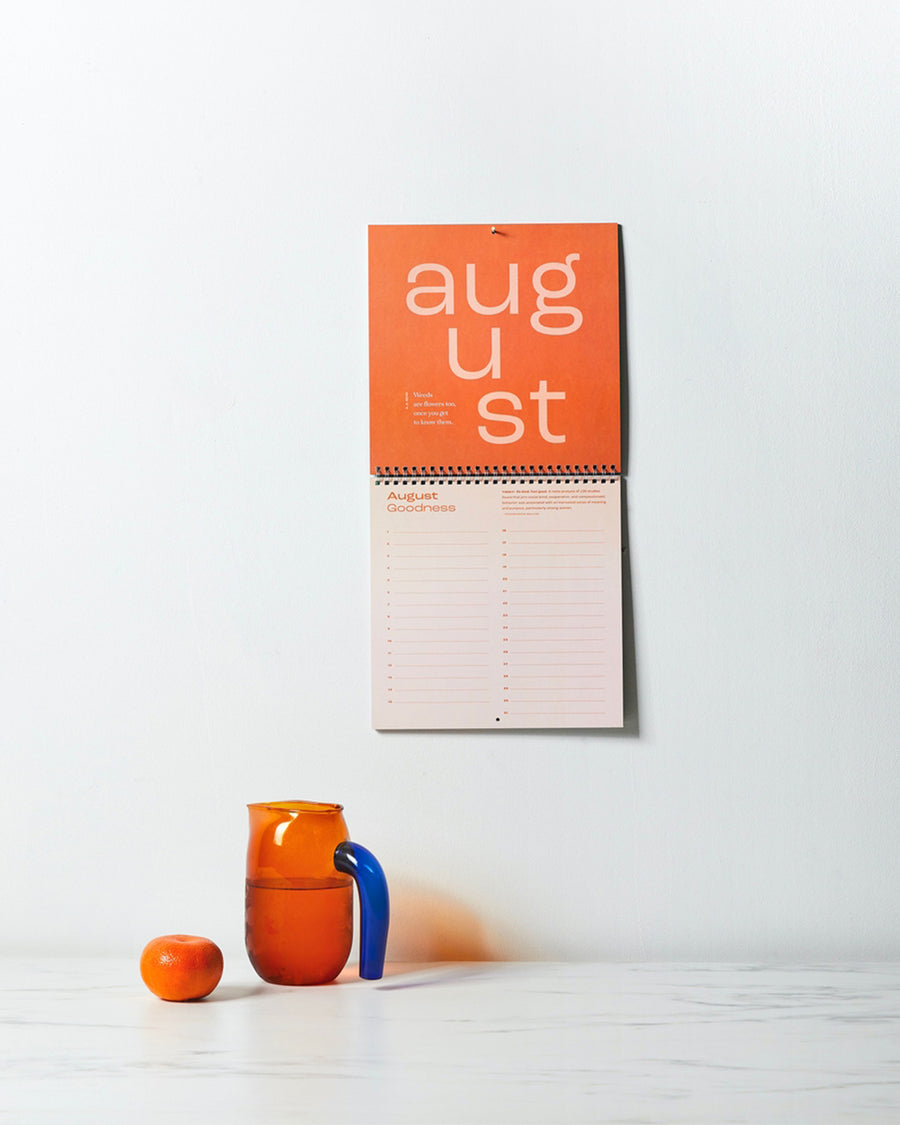 calendar of good: gratitude calendar hanging on wall with pitcher and apple on counter