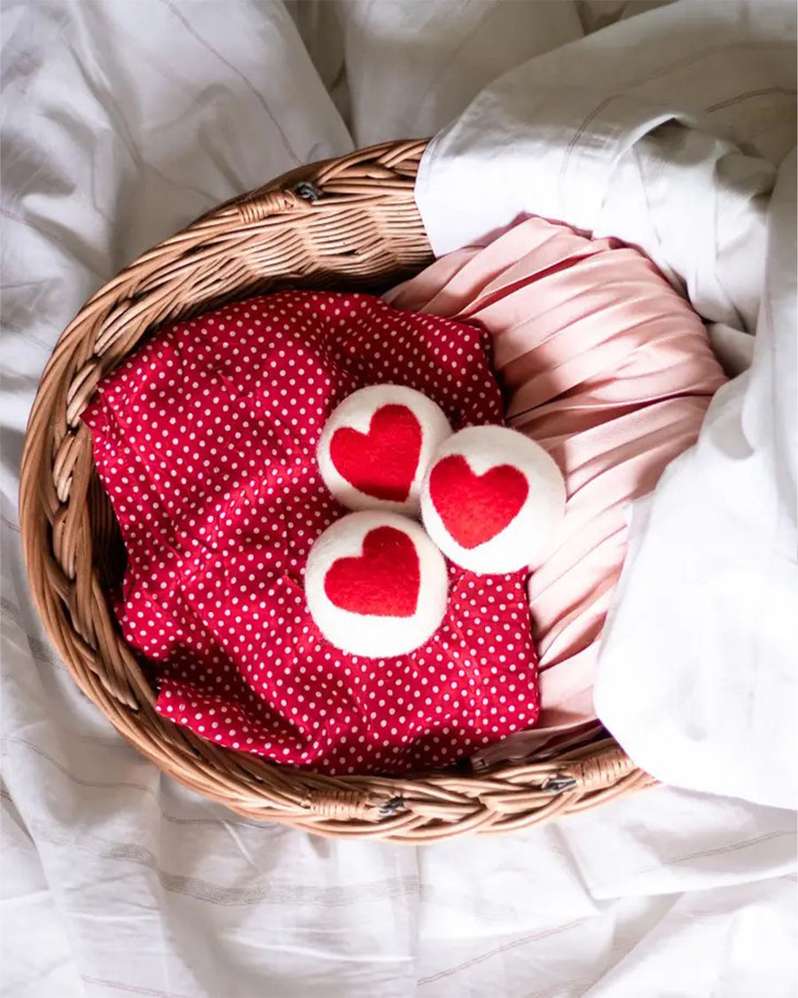 set of three white laundry balls with a large red heart in the center