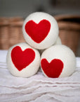 set of three white laundry balls with a large red heart in the center