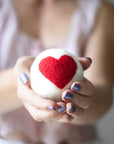 model holding white laundry ball with a large red heart in the center