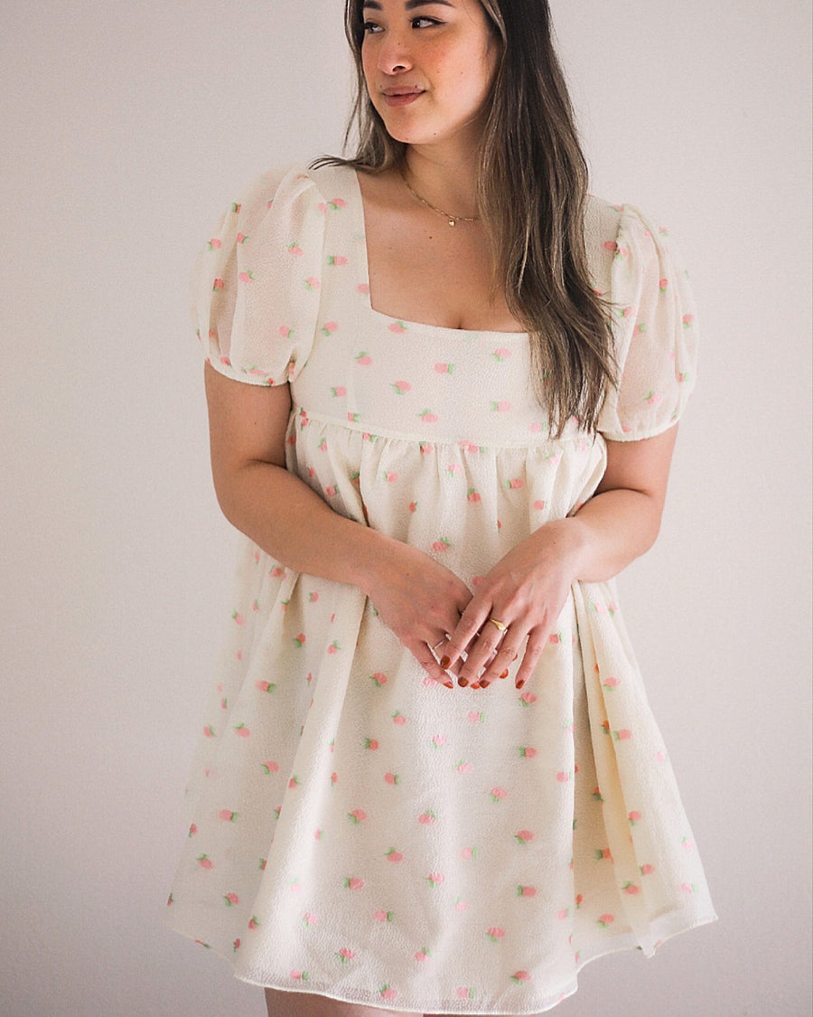 model wearing white mini dress with puff sleeves and all over pink fruit print